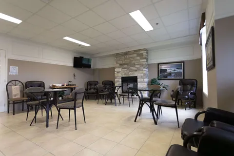 Common room with tables, chairs and a stone fireplace.