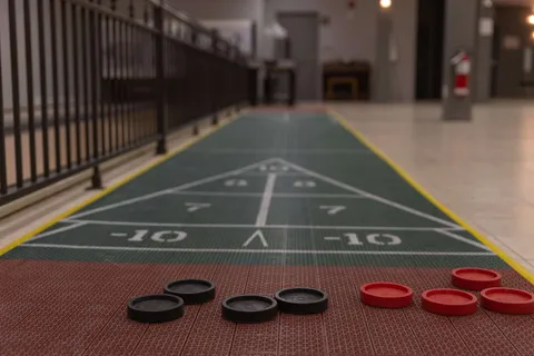 Indoor shuffleboard lane with discs on the floor.
