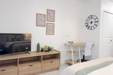 Suite living corner with television cabinet, desk and upholstered seating.