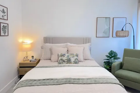 Bedroom with double bed, bedside tables and green armchair.