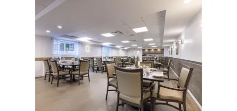 Dining room with set tables and upholstered chairs.