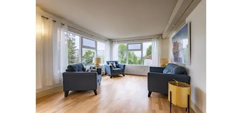 Lounge with armchairs, sofas and large windows.