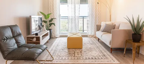 Living room with a sofa, television, armchair and balcony doors.