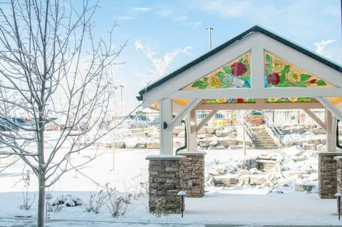 Wooden gazebo with stained glass panels beside a snow-covered courtyard