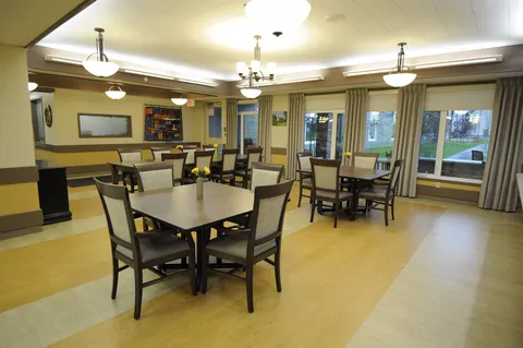 Dining room with tables, chairs, wide windows and colourful quilts