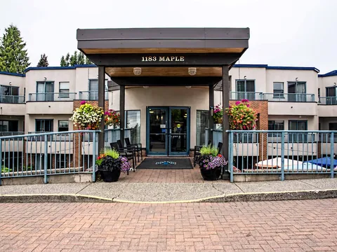 Covered entrance with glass doors and flower planters.