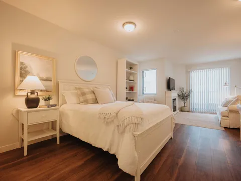 Furnished suite with a bed and sitting area beside windows.