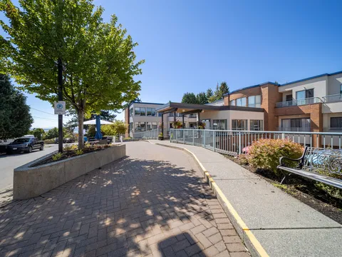 Residence facade beside a tree-lined paved walkway.