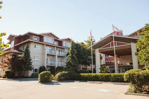 Residence exterior with balconies, a covered entrance, flagpoles and landscaping.