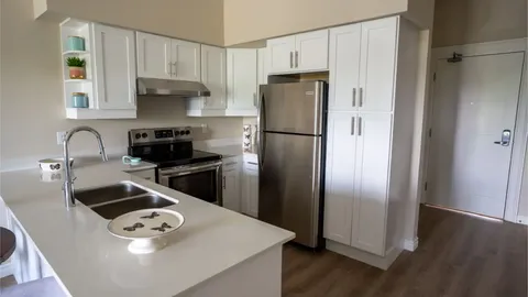 Suite kitchen with white cabinets, appliances and a breakfast counter.