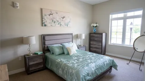 Bedroom with a double bed, dressers and a large window.