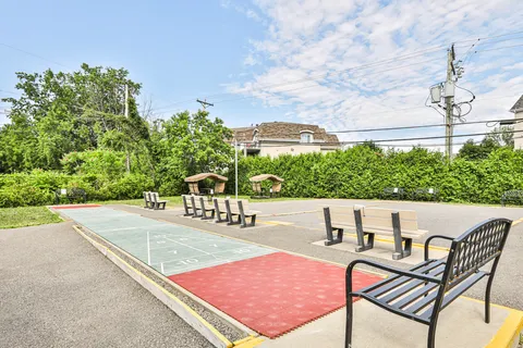 Outdoor game court with benches, swings and surrounding hedges