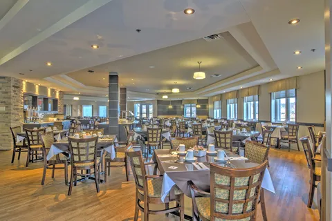 Dining room with set tables, wooden chairs, ceiling lights and large windows