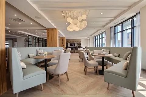 Bistro dining area with pale chairs beside large windows.