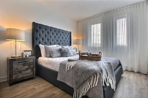 Bedroom with a grey upholstered bed and bedside lamps.