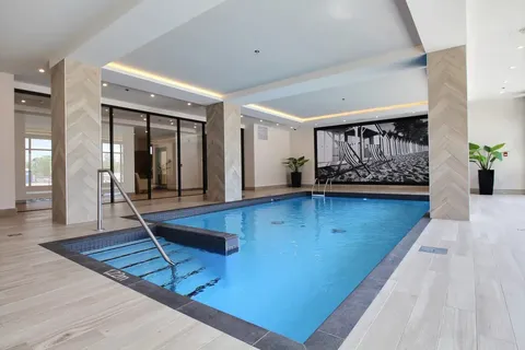 Indoor swimming pool with railings and tiled surroundings.