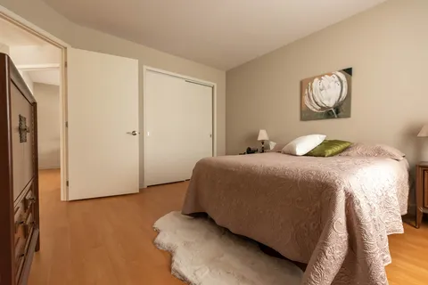 Bedroom with a double bed, pale pink bedspread, white closet and flower artwork