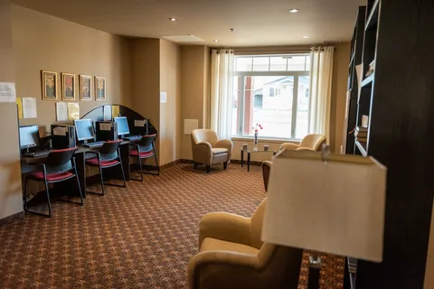 Computer area with desktop monitors, chairs, armchairs and a large window