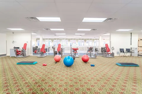 Exercise room with red fitness machines, exercise balls and floor mats