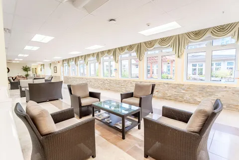 Bright sitting area with wicker chairs, a glass coffee table and a long row of windows