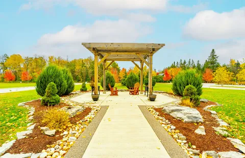 Garden path leading to a wooden pergola with two chairs