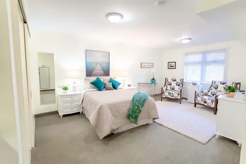 Bedroom with a double bed, teal cushions, two armchairs and a window