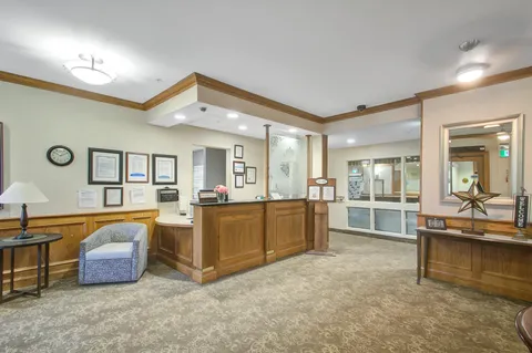 Reception area with a wooden desk, upholstered chair and mirrors