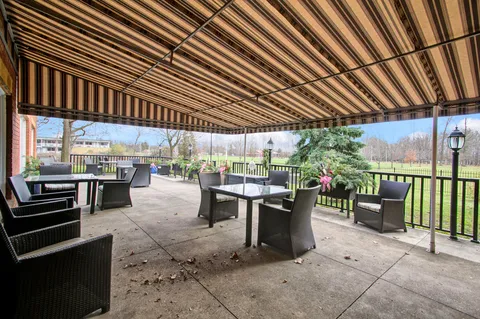 Covered patio with wicker chairs, tables and views of the lawn