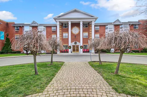 Brick residence with a columned central entrance, lawn and paved walkway