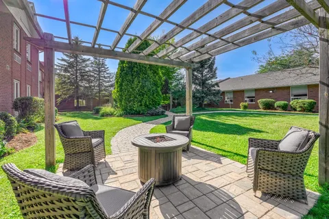 Patio with wicker chairs, a pergola and surrounding lawn