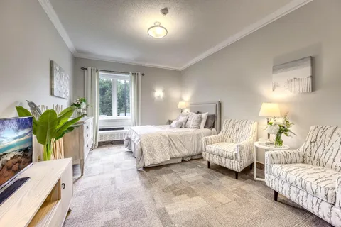 Bedroom with a bed, two patterned armchairs and a television