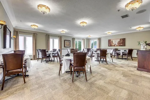 Dining room with wooden tables, upholstered chairs and framed landscape pictures