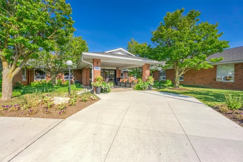 Brick residence entrance with a covered driveway and landscaped beds