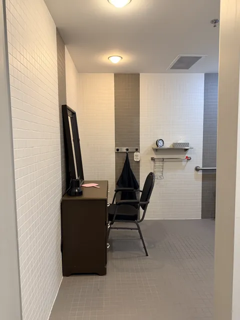 Salon with a mirror, styling chair and hair-drying equipment.