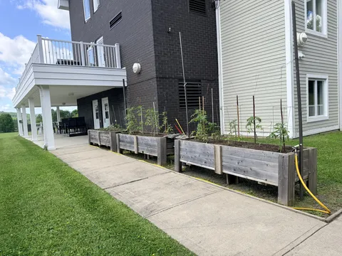 Raised garden beds along a paved walkway beside the residence.