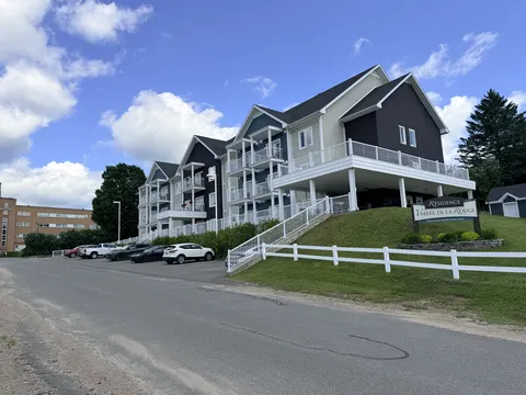 Residence facade and balconies with a ramp, steps and parking area.