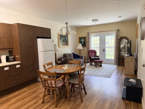 Suite kitchen, dining table and sitting area beside glazed patio doors.