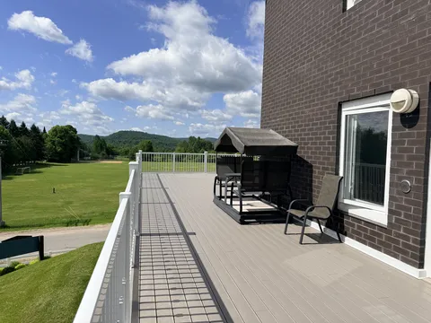 Upper terrace with white railings, chairs and a covered garden swing.