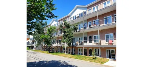 Rear of a brick residence with balconies overlooking trees and a lawn