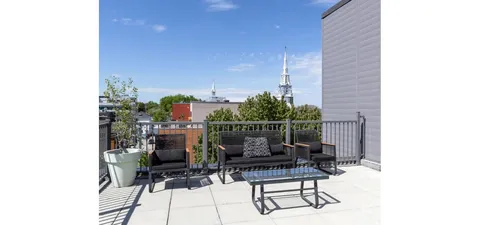 Terrace with chairs and railings overlooking nearby trees and buildings