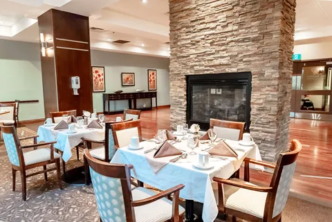 Dining tables set beside a stone fireplace and framed floral pictures