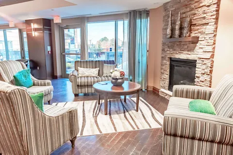 Armchairs around a coffee table beside a stone fireplace and patio doors