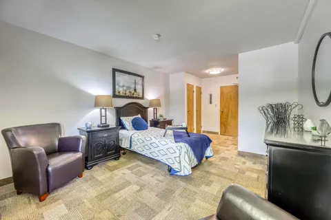 Bedroom with a blue-covered bed and two leather armchairs