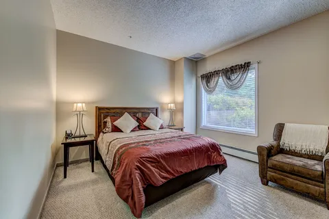 Bedroom with a bed, nightstand and curtained window.