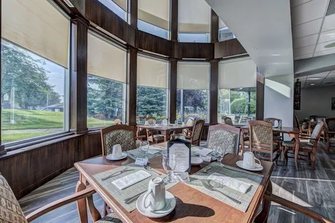 Dining tables beside tall windows overlooking the grounds.