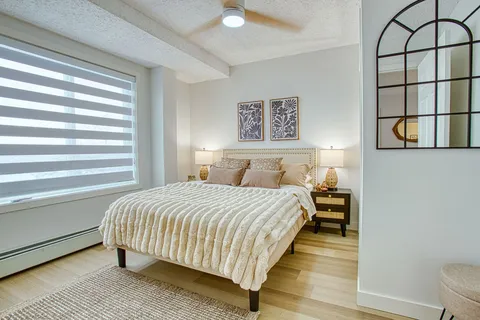 Bedroom with a bed, dresser and window blind.