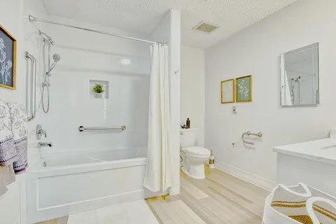 Bathroom with a bathtub, grab bars, toilet and vanity.