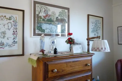 Bedroom dresser with a lamp and framed artwork.