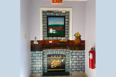 Interior exit doorway painted with a fireplace and rural scene.