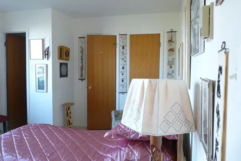 Bedroom with a bed, lamp and wooden closet doors.